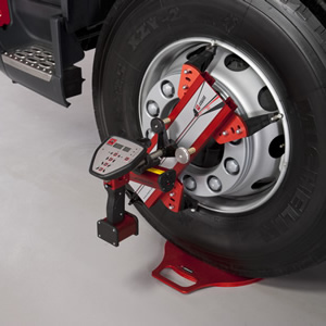A red truck tire being held on a wheel stand, showcasing the tire's vibrant color and its secure placement.